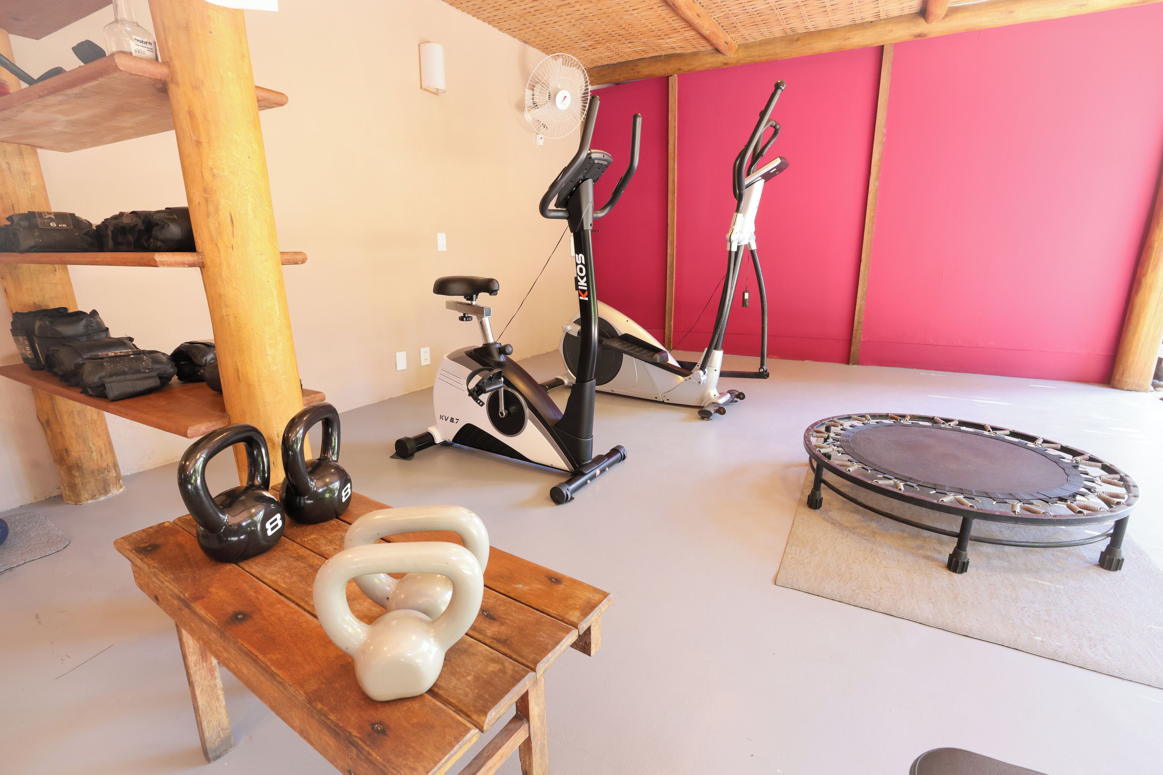 A home gym with exercise equipment including kettlebells, a treadmill, and a trampoline.