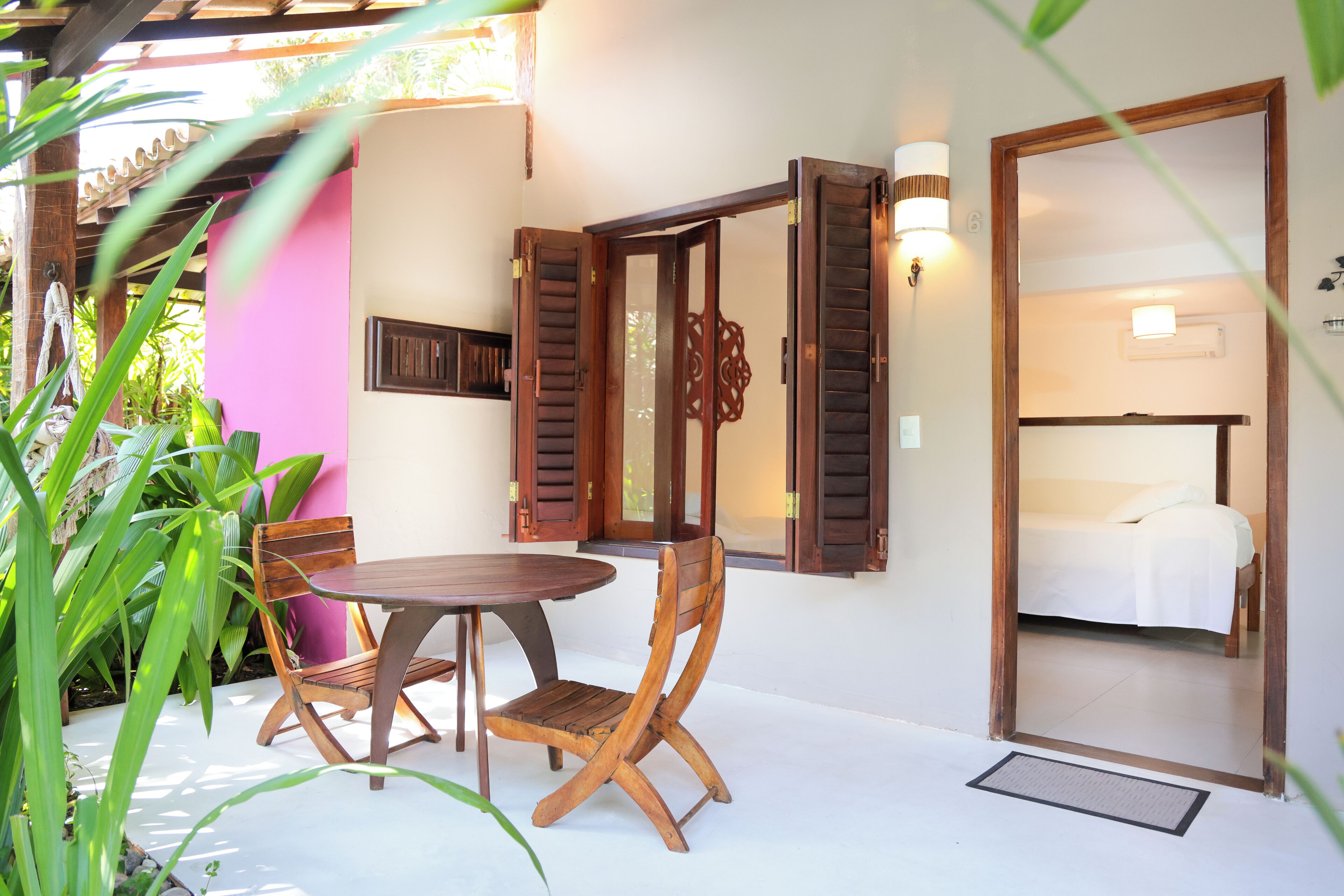 A room with a bed, a wooden table, and chairs.