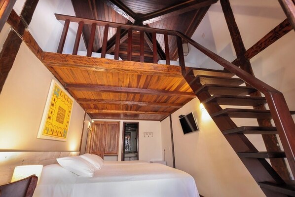 Un dormitorio con techo de madera y una escalera.