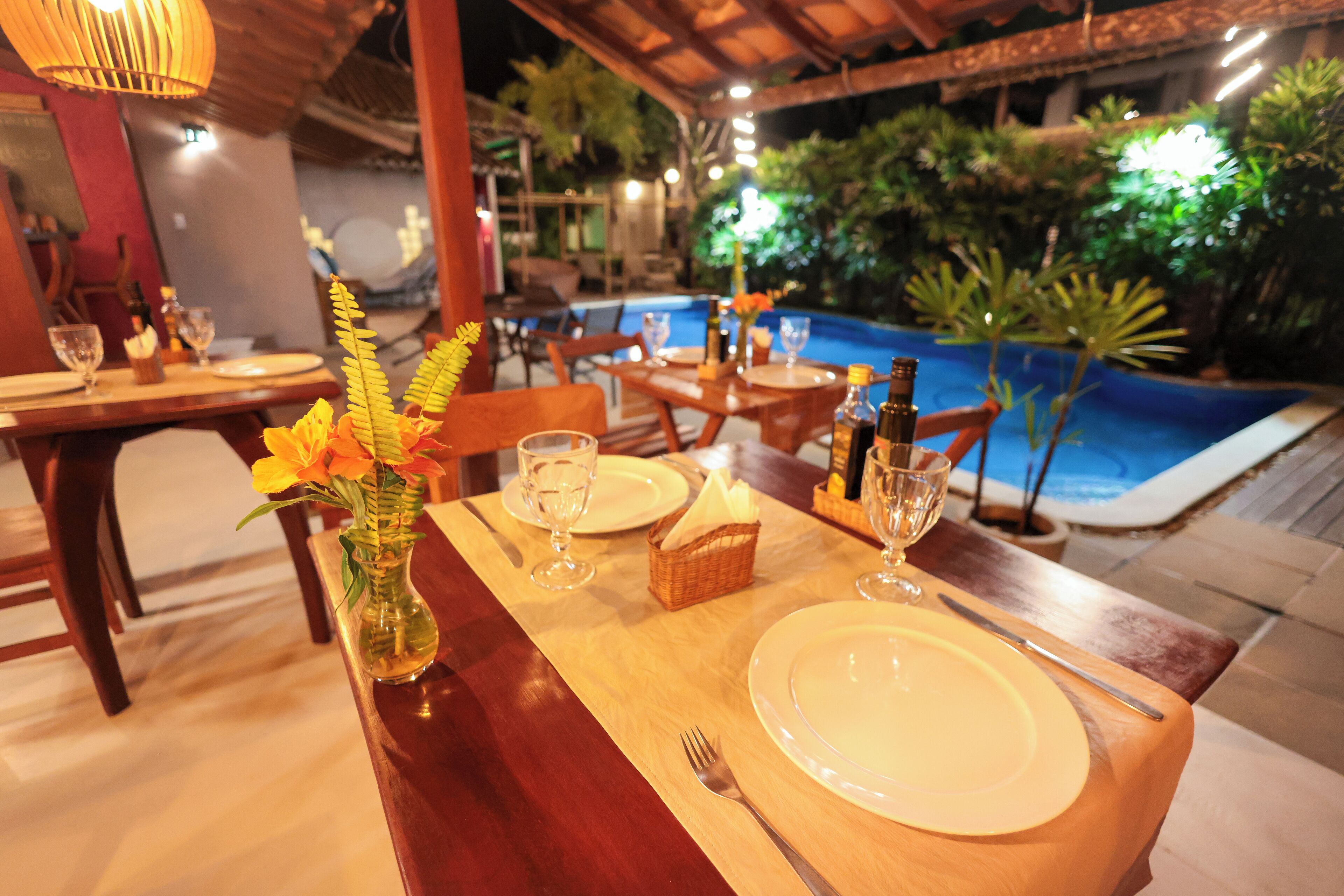 Comedor con mesas dispuestas para dos, con vista a la piscina.
