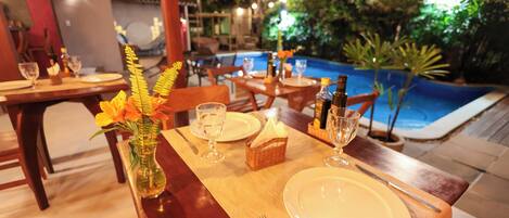 Comedor con mesas dispuestas para dos, con vista a la piscina.