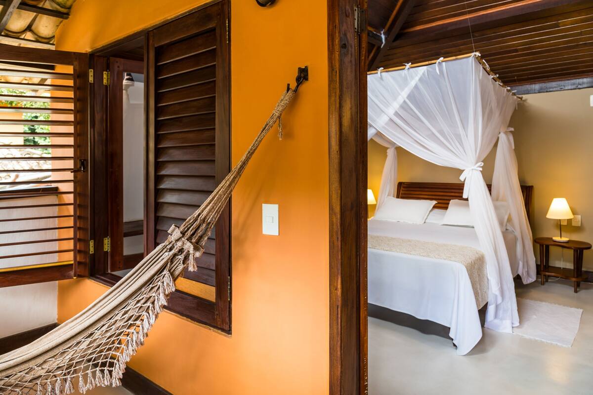 A room with a bed, a hammock, and a canopy bed.