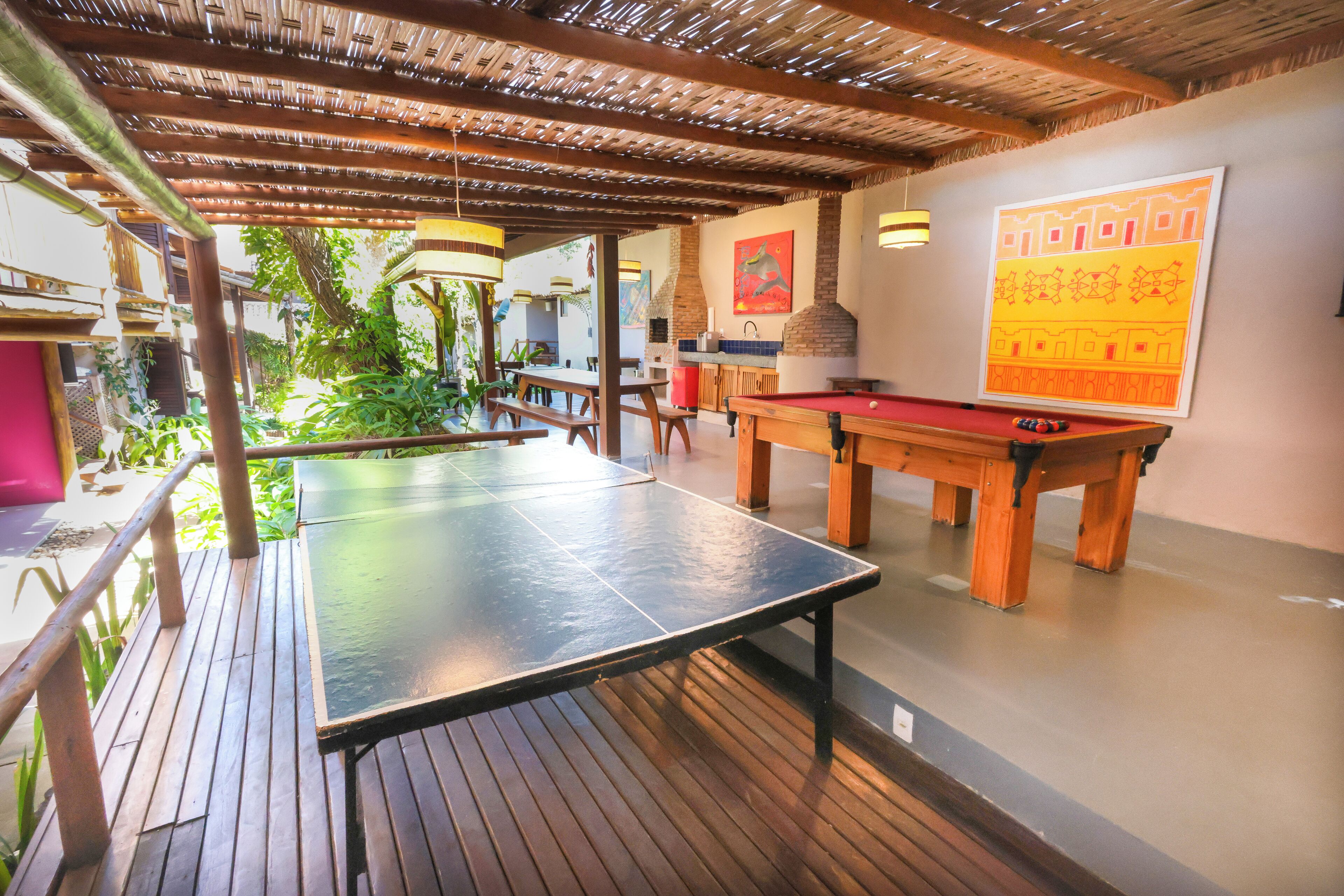 Un espacio recreativo interior con mesa de ping pong, mesa de billar y una parrilla.