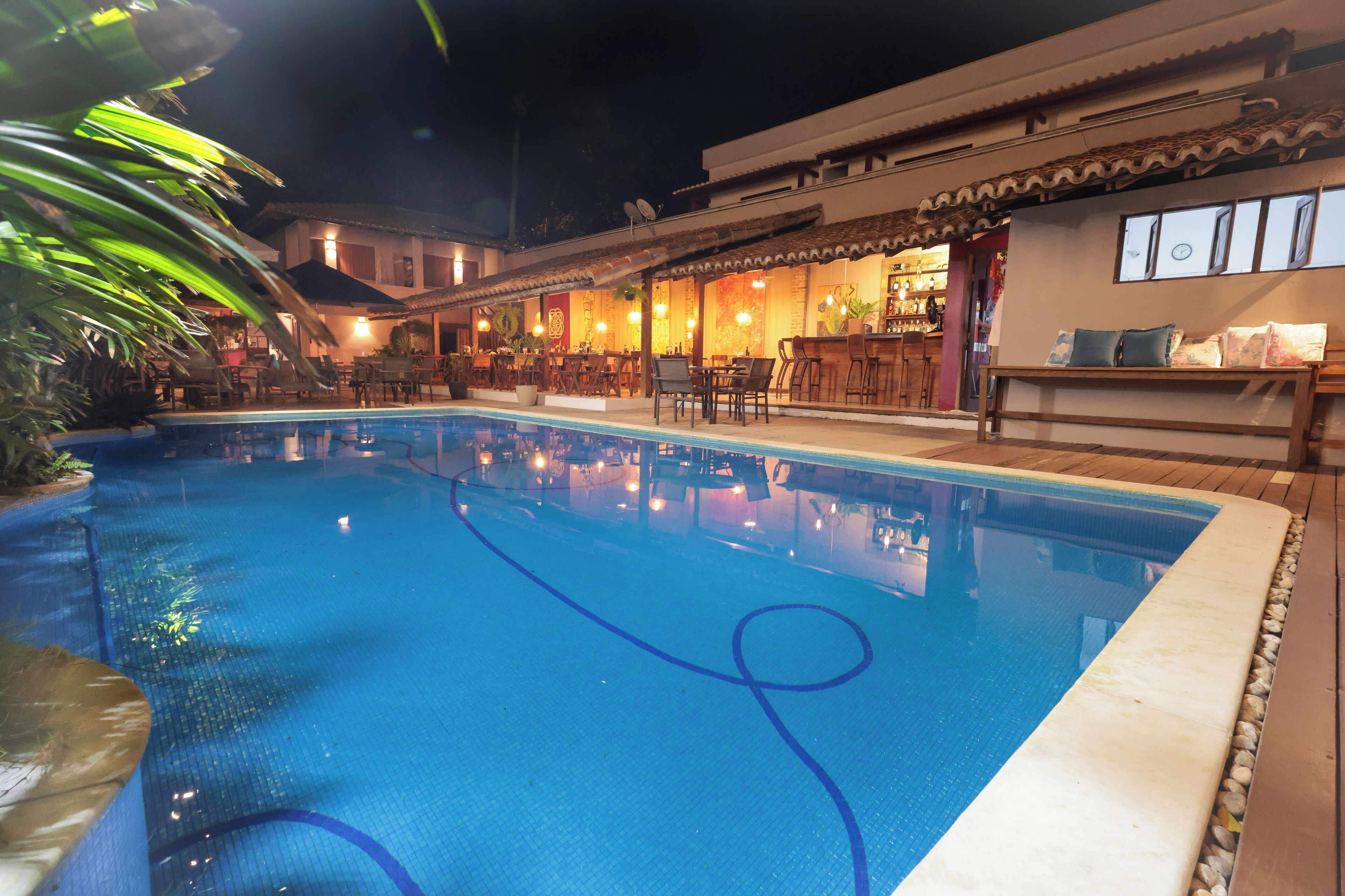 A swimming pool with a bar and seating area adjacent to a building with traditional architecture.