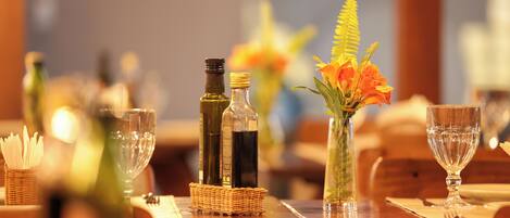 A dining table set with wine bottles, a vase with flowers, and empty glasses.