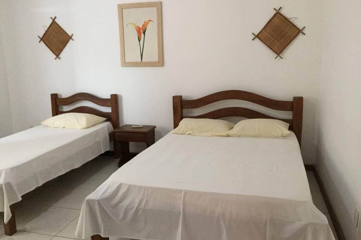 A room with two single beds, a small bedside table, and a framed picture on the wall.