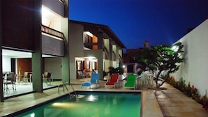 A modern outdoor pool area with a clear pool, lounge chairs, and a building with multiple levels and outdoor seating. - Pousada Costa Marina (Fortaleza)