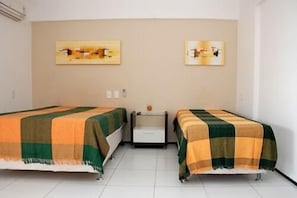 Ein Hotelzimmer mit zwei Betten, jeweils mit einer karierten Decke, einem kleinen Nachttisch und zwei Wandbildern.