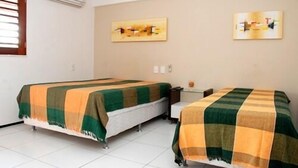 A hotel room with two beds, each covered with a green and orange checkered blanket. There are two paintings on the wall, one above each bed. - Pousada Costa Marina (Fortaleza)