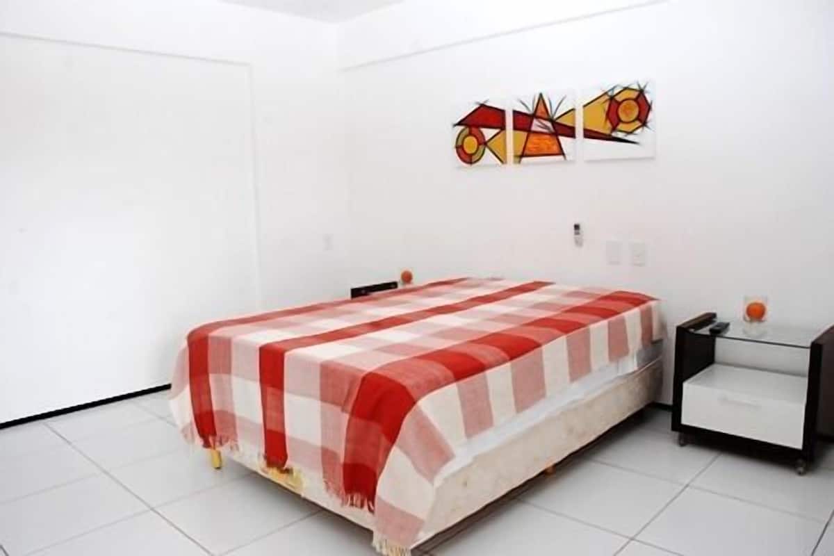 Une chambre à coucher comprenant un lit, une table de chevet et une œuvre d’art accrochée au mur.