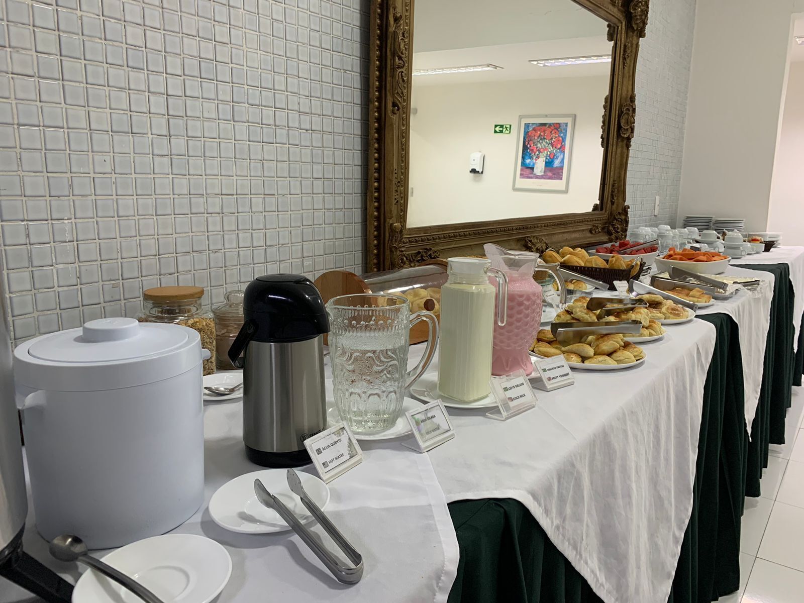 A buffet table with various food items, a coffee maker, and a water pitcher.