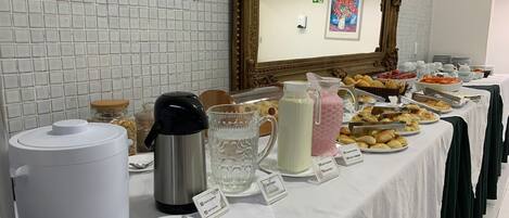 A buffet table with various food items, a coffee maker, and a water pitcher.