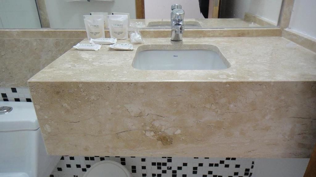 A bathroom with a marble sink, a mirror, and toiletries on the countertop.