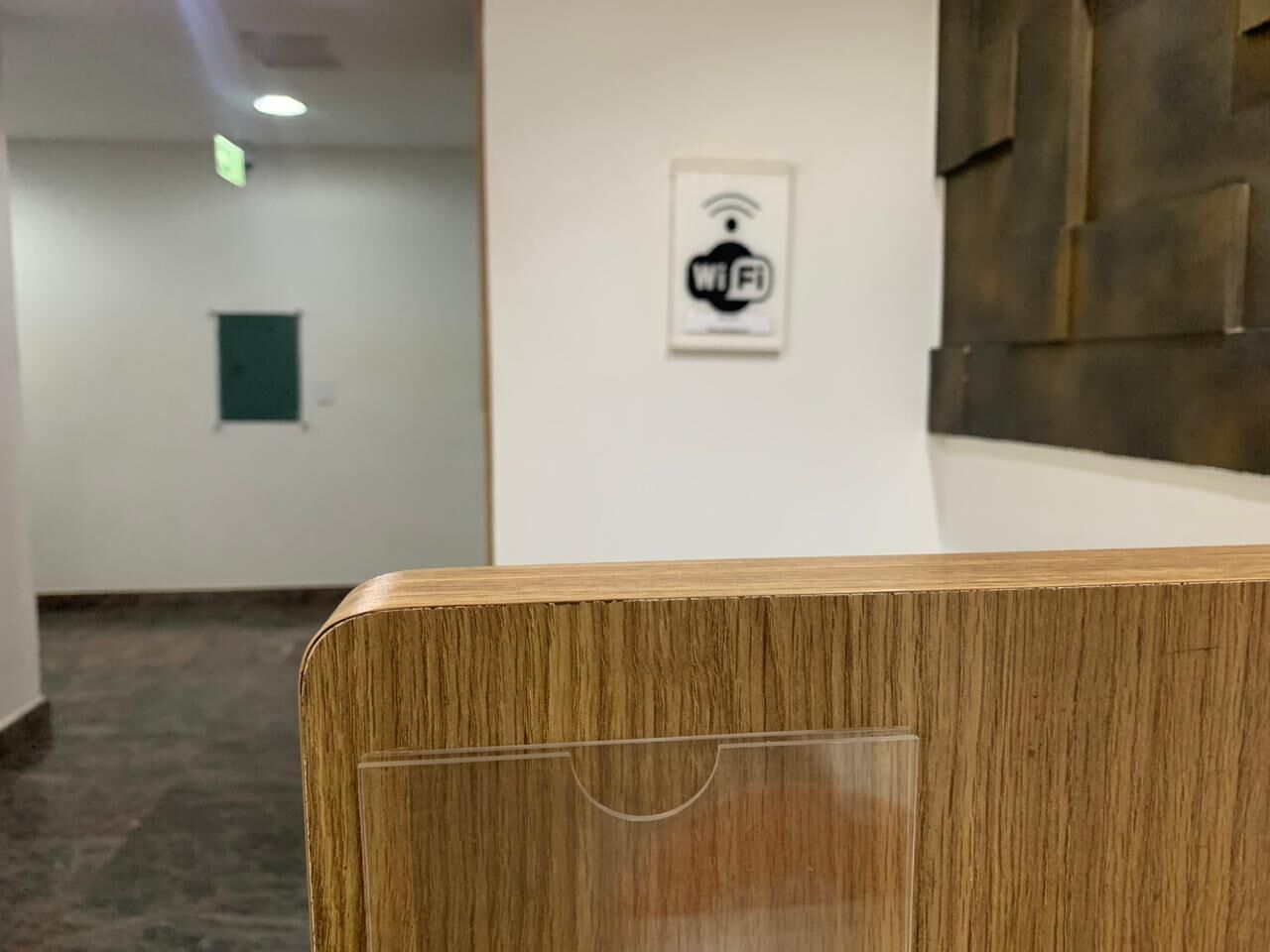 A wooden reception desk with a Wi-Fi symbol on the wall behind it.