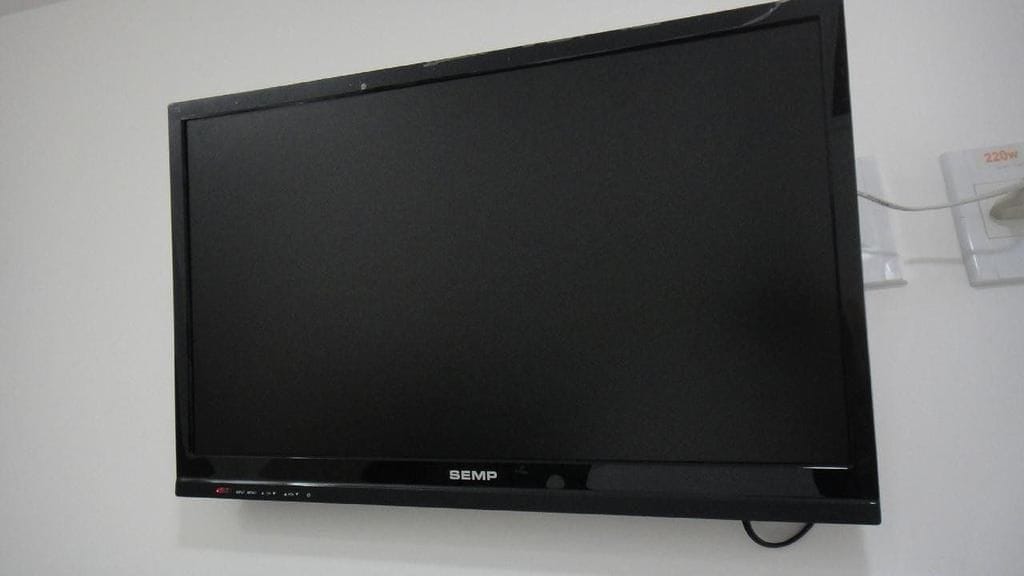 Un televisor de pantalla plana negra montado sobre una pared blanca.