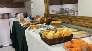 A buffet setup with various food items and a large mirror. - Syros Hotel (Gama)