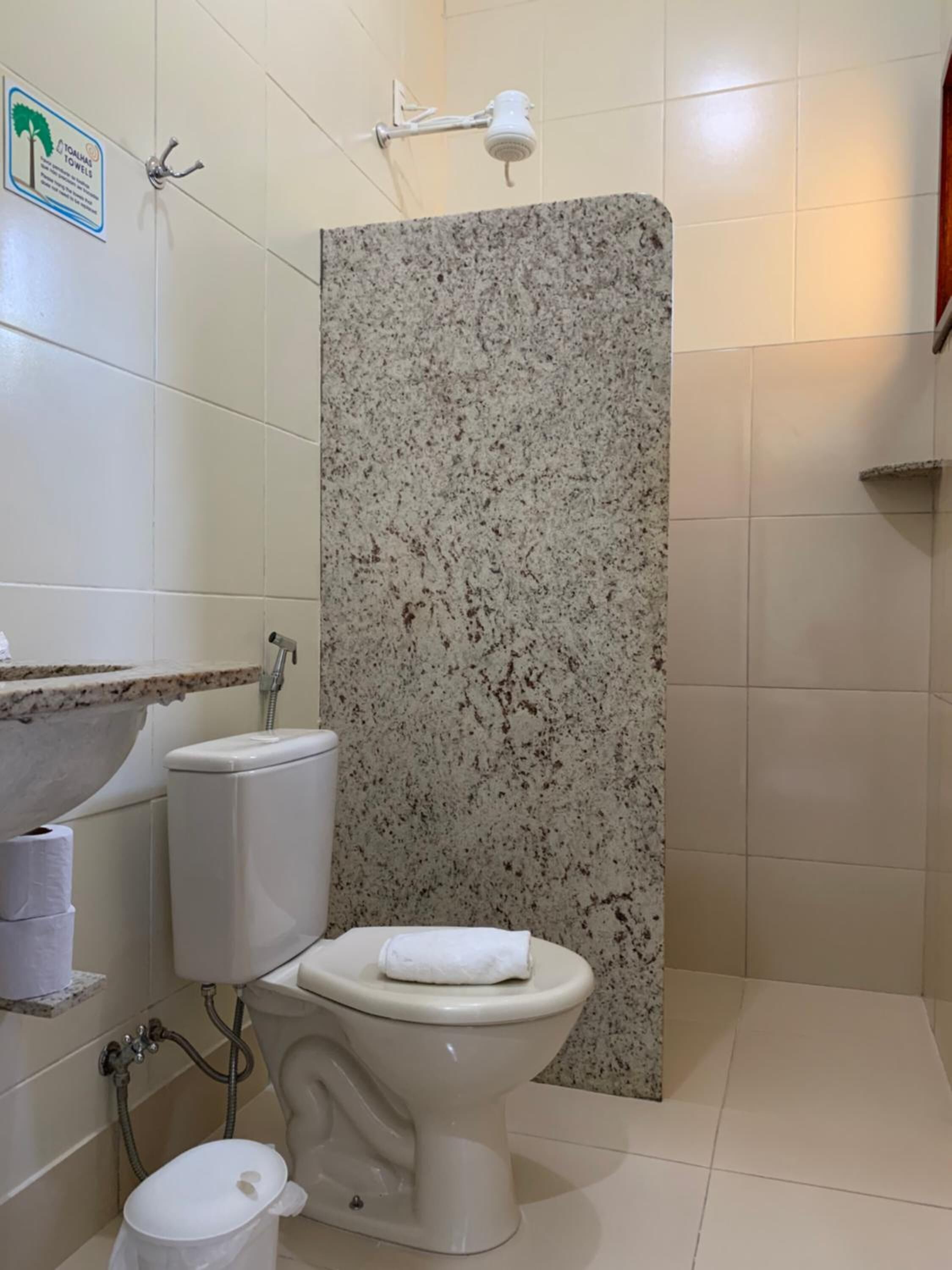 Une salle de bain comprenant des toilettes, un lavabo et un espace douche.