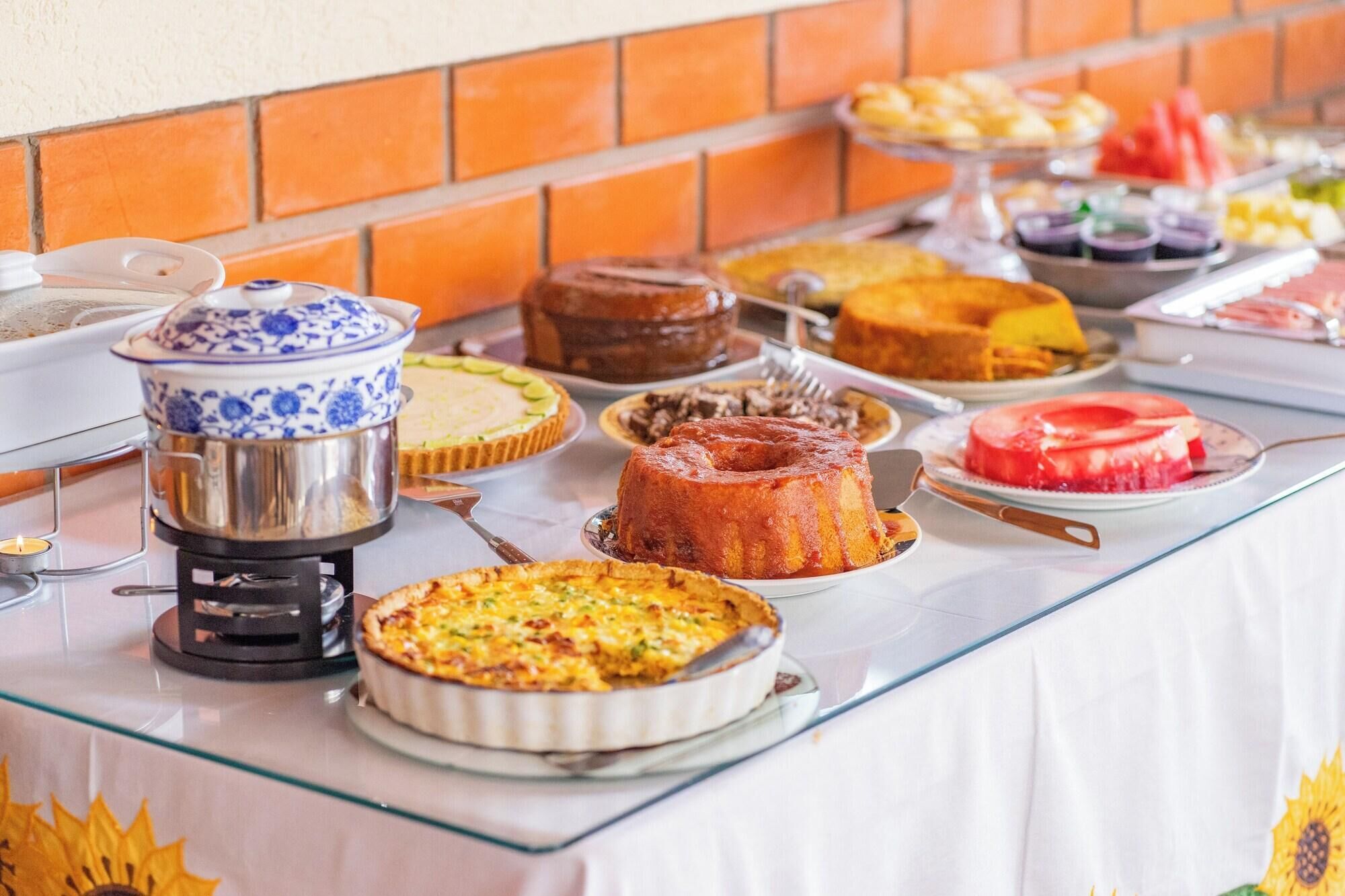 A buffet table with various dishes, including a cake, a quiche, and a pie.