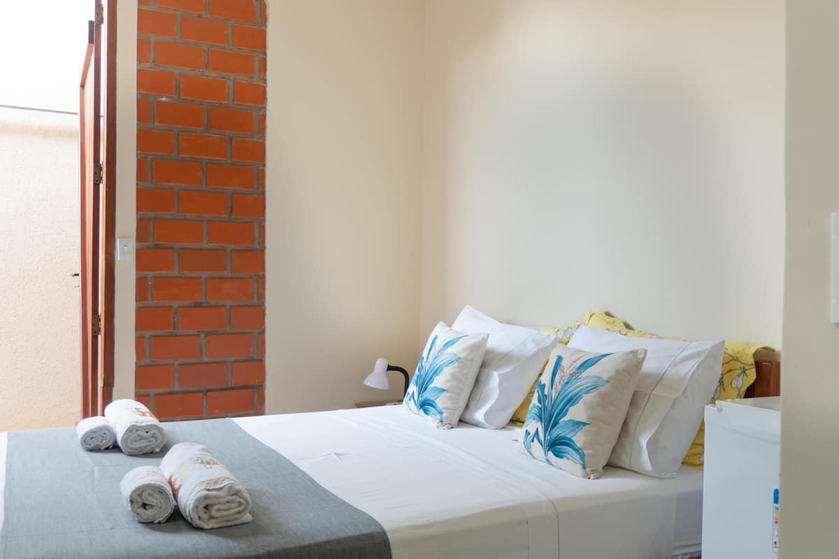 Ein Hotelzimmer mit Bett, Kissen, einer Lampe und einem Handtuchhalter.