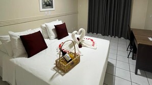 Una habitación de hotel con una cama bien hecha, una mesa de comedor y un ventanal con cortinas.