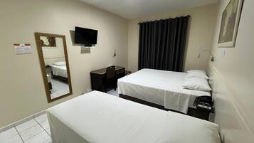 Una habitación de hotel con dos camas individuales, un escritorio, una silla, un televisor y un espejo.
