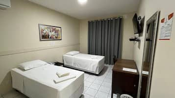 Una habitación de hotel con dos camas, un escritorio pequeño, un espejo y un cuadro en la pared.