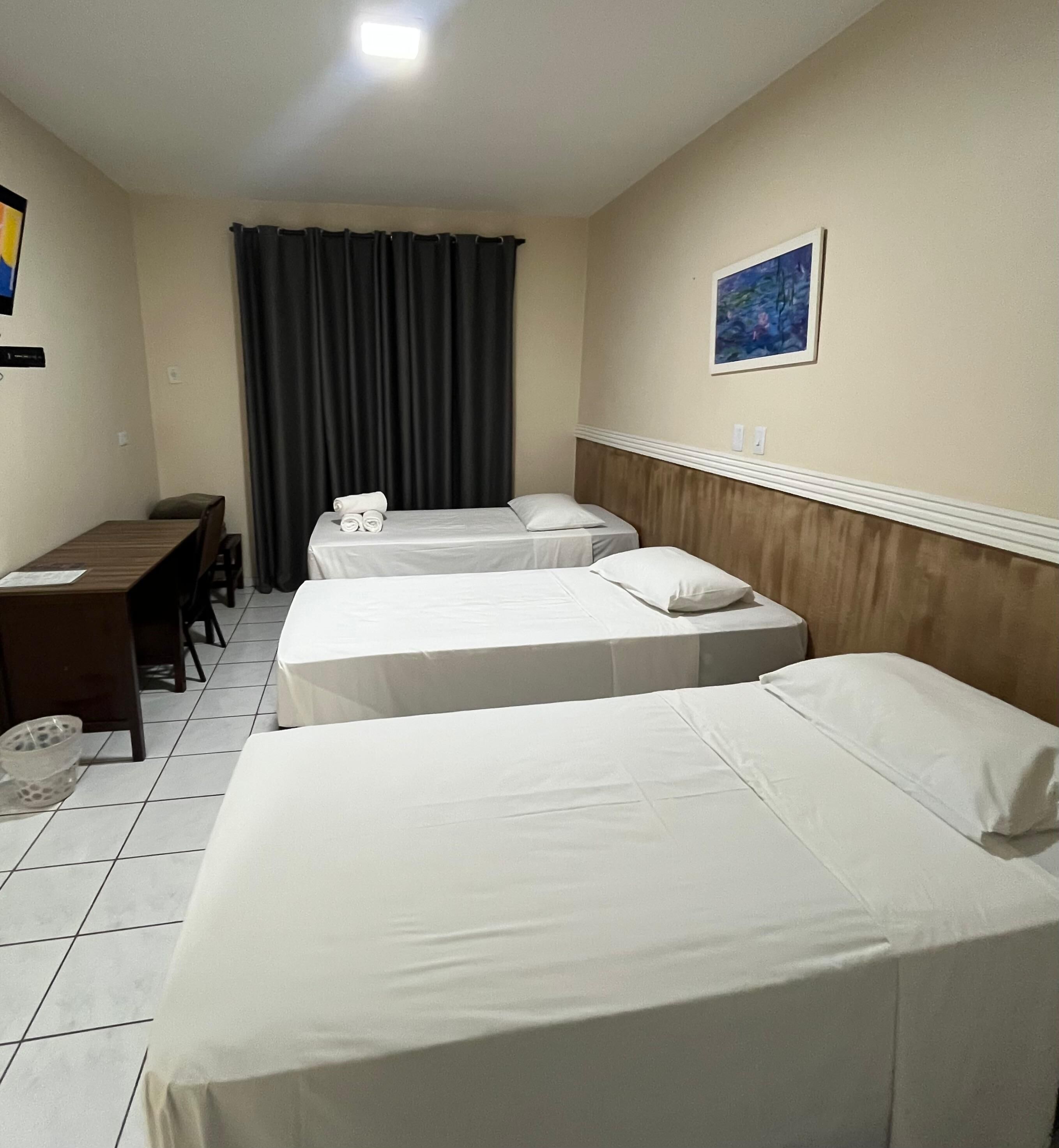 A hotel room with two single beds, a desk, and a chair.