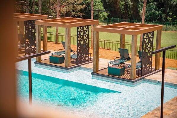 A pool area with multiple lounge chairs and wooden pergolas. - Hotel Pousada do Bosque (Ponta Porã)