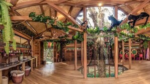 Una habitación con techo de madera, una estructura de árbol en el centro y varias figuritas de animales.