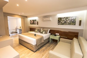 Une chambre d’hôtel moderne avec un grand lit, une table de chevet, une chaise et un canapé.