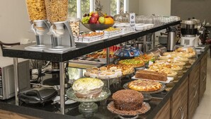 A buffet with various food items and a coffee station. - Hotel Tainá - Aeroporto Cuiabá (Varzea Grande)