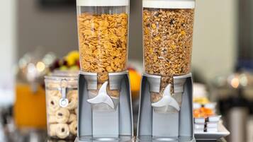 Three cylindrical dispensers filled with different types of cereal flakes.