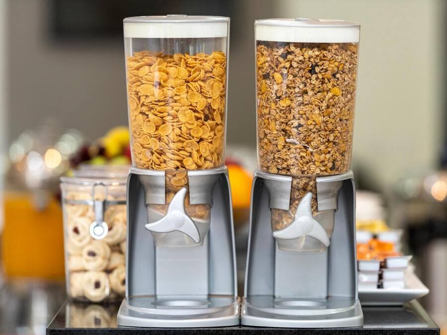Three cylindrical dispensers filled with different types of cereal flakes.