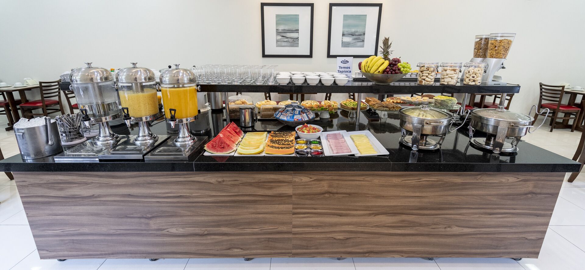 A buffet setup with various food items and beverages, including fruits, pastries, and a coffee station.