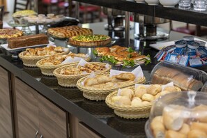 A buffet with various baked goods and sandwiches. - Hotel Tainá - Aeroporto Cuiabá (Varzea Grande)