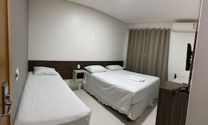 A hotel room with two single beds, a small bedside table, a desk, and a chair.