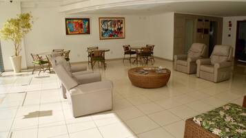 Uma sala de estar espaçosa com sofá, cadeiras, mesa de jantar e obras de arte nas paredes.