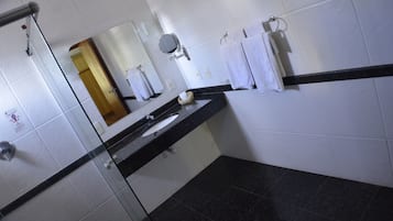 Une salle de bain avec un comptoir noir, des carreaux blancs, un miroir et un porte-serviettes.