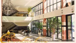 A spacious lobby with a chandelier, large windows, and potted plants. - Constantino Hotel (Juiz de Fora)