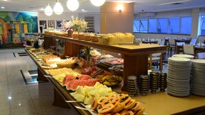 A buffet with various food items and a seating area with tables and chairs. - Constantino Hotel (Juiz de Fora)