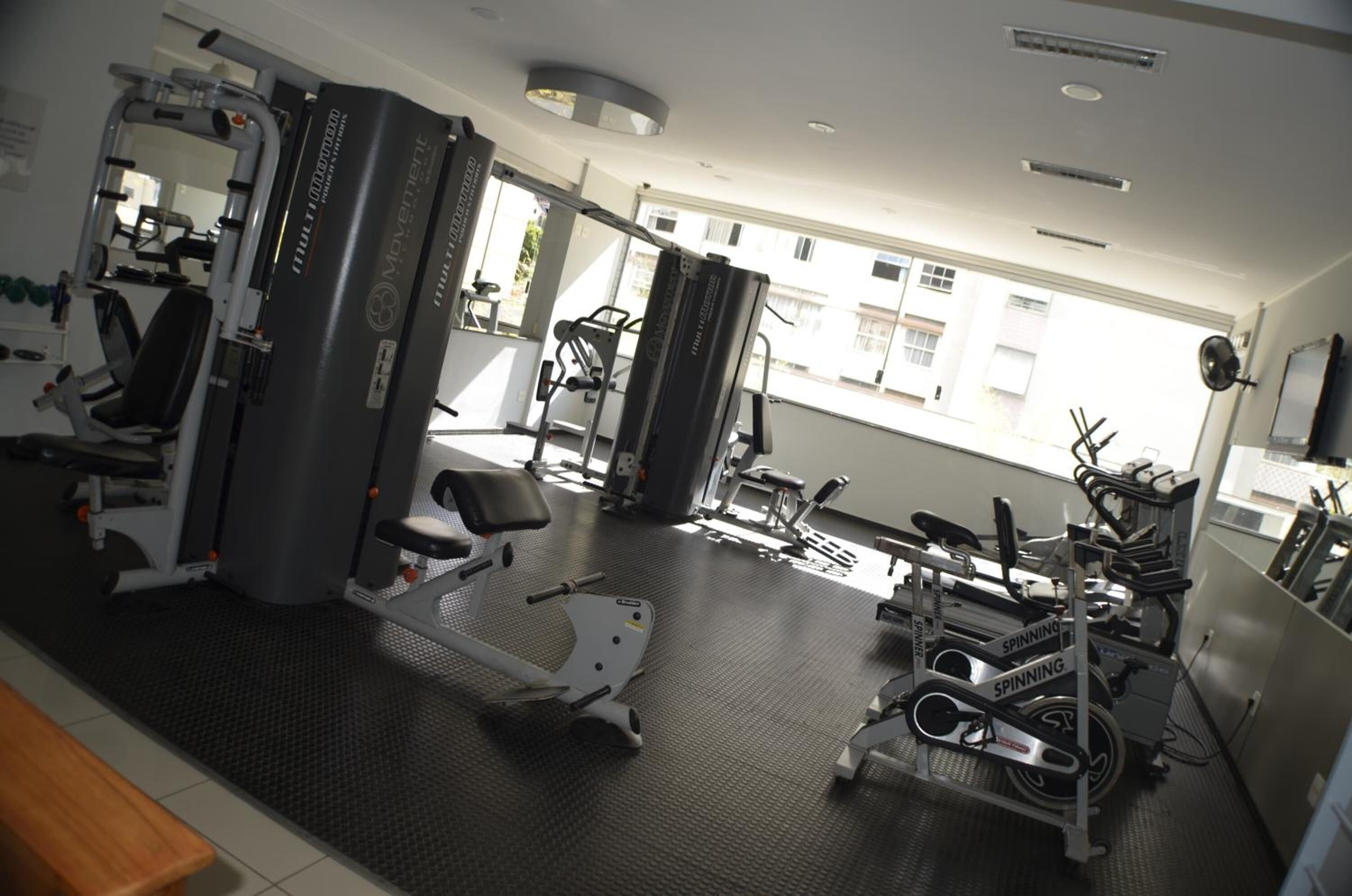 A gym with various exercise equipment, including a spinning bike and a weight machine.