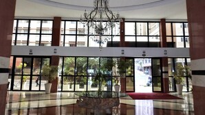A spacious lobby with a chandelier, large windows, and a central glass table. - Constantino Hotel (Juiz de Fora)