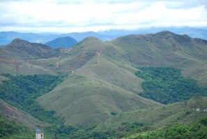 Un paisaje montañoso con un sendero sinuoso y una pequeña estructura tipo torre.