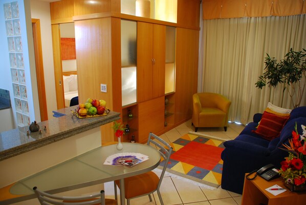 Un espacio habitable compacto con comedor, sofá y pequeña cocina.