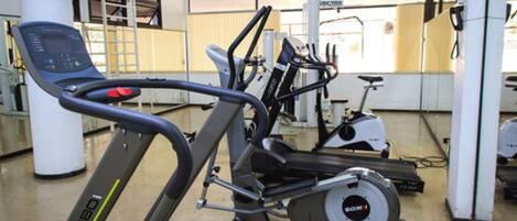 Un gimnasio con máquinas de cardio, incluyendo una cinta de correr y una elíptica.