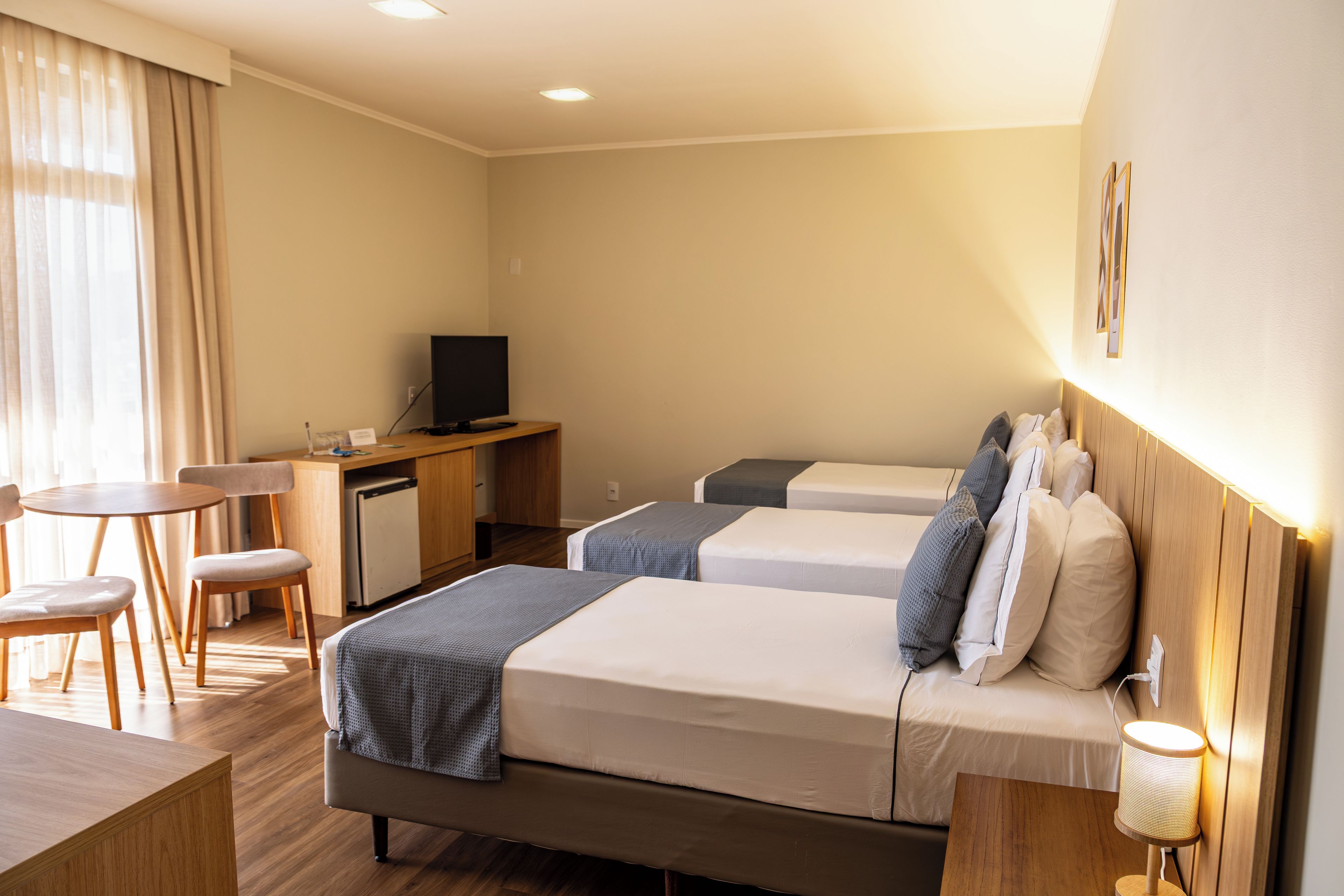 Una habitación de hotel con dos camas, un escritorio, un televisor y una zona de comedor.