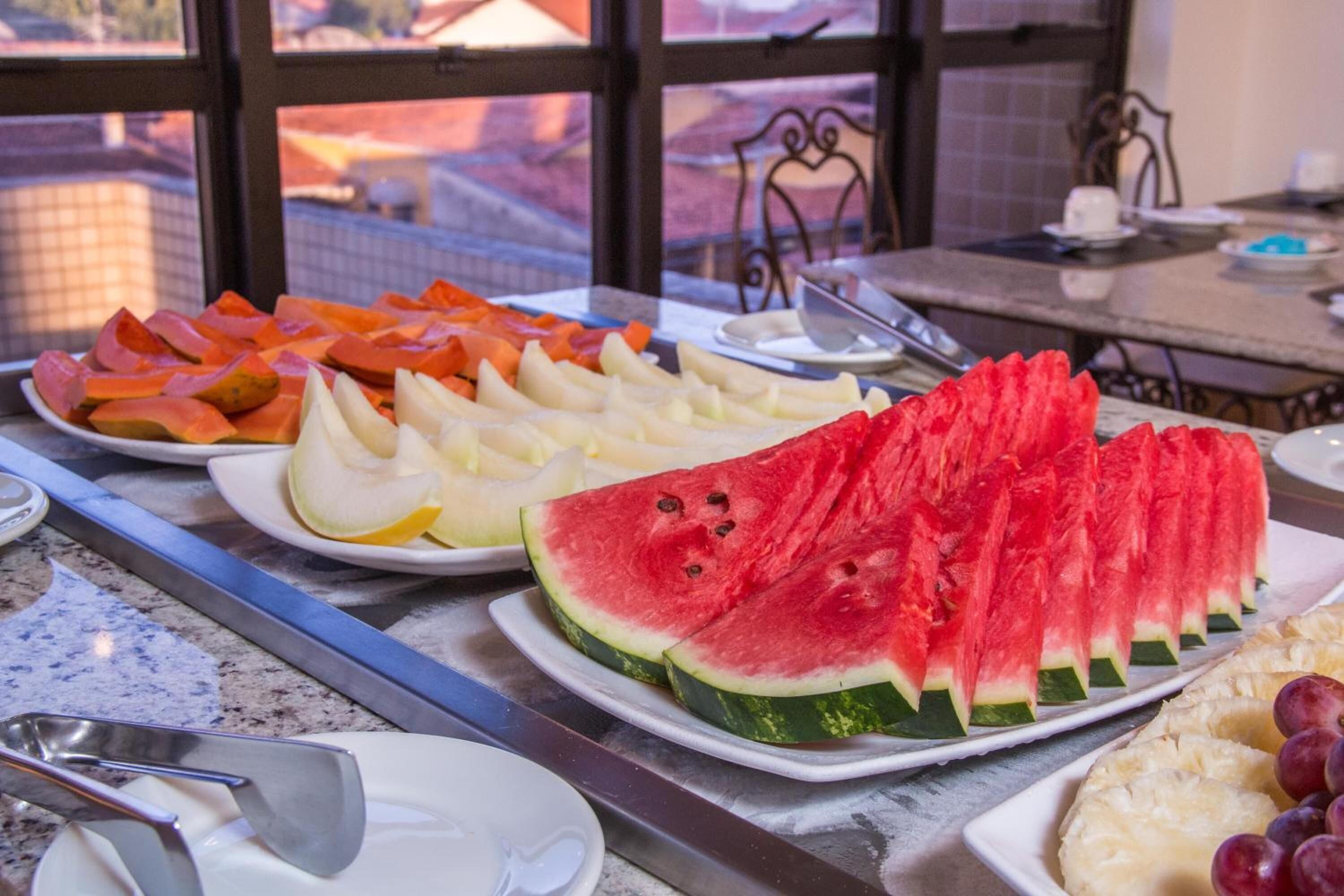 Una mesa de buffet con diversas frutas y una gran sandía como pieza central.