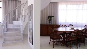 A dining area with a round table, six chairs, and a vase with flowers.