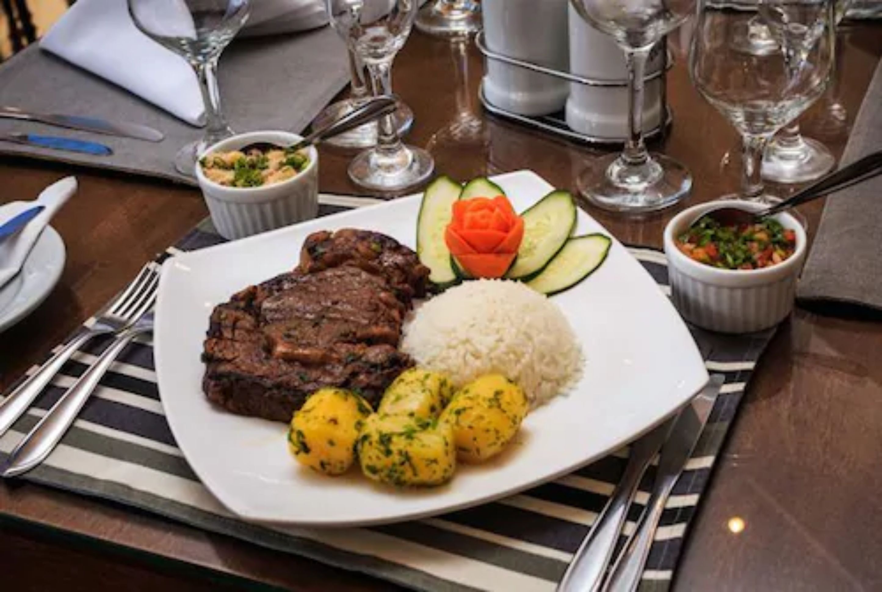 Ein Teller Essen mit Fleisch, Reis und gekochten Kartoffeln.