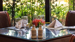 Een eettafel gedekt met glazen, servetten en een bloemstuk.